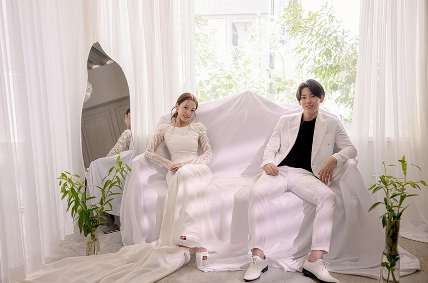白いカーテンの部屋のソファに座る新婦と新郎