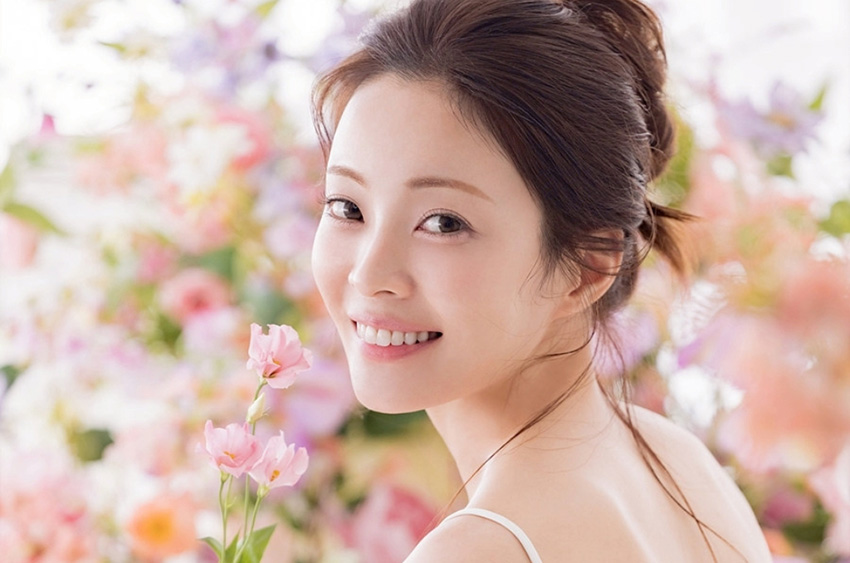 ピンクの花に囲まれ微笑む新婦のアップ