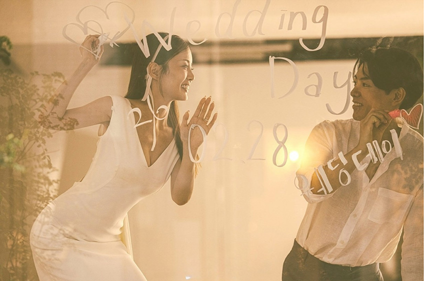 ガラスにWedding Dayの文字を書きながら微笑む新郎新婦